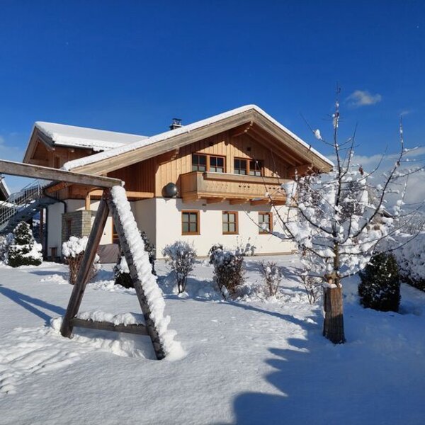 The Farm House in winter, featuring snow-covered grounds, a garden, and views of the surrounding mountains.