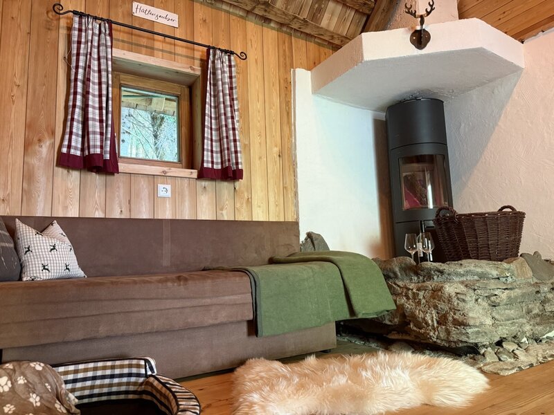 Cozy living area of the bed and breakfast, featuring an inviting sofa, rustic wood-paneled walls, and a warming fireplace.