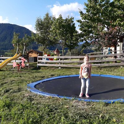 Children's outdoor play area at the farmhouse with a trampoline, slide, and spring rider.