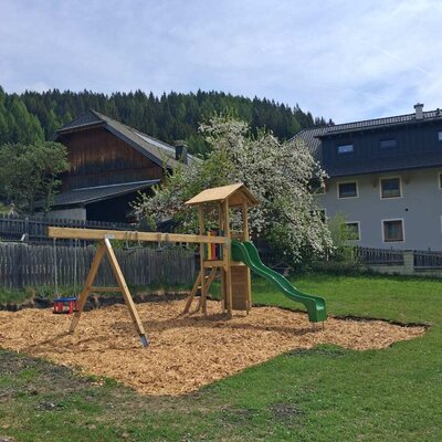 The playground at the farmhouse with a swing, slide, and wood chip safety surface.