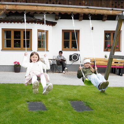 Children's playground at the farmhouse with swings and a grassy area.