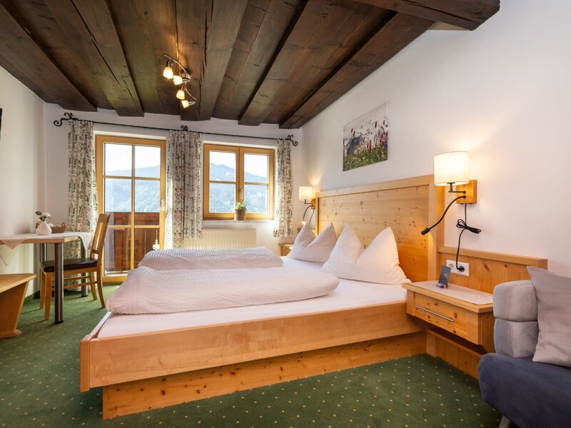 Double room in the farmhouse with wooden beam ceiling, double bed, seating area, cable TV, and balcony access with mountain views.