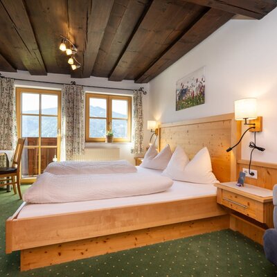 Double room in the farmhouse with wooden beam ceiling, double bed, seating area, cable TV, and balcony access with mountain views.
