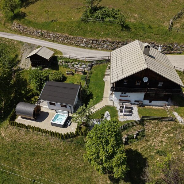An aerial view of the idyllic Alm featuring an inviting outdoor sauna and a modern hot tub in the manicured garden area.