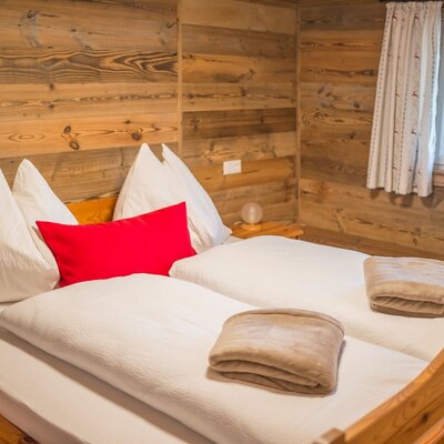 A cozy bedroom in the Alm featuring rustic wooden walls, a comfortable double bed, and soft bedding.