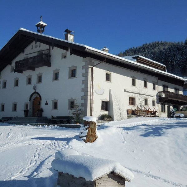 The Farm House exterior during winter, showing the snow-covered grounds and wooden balconies.
