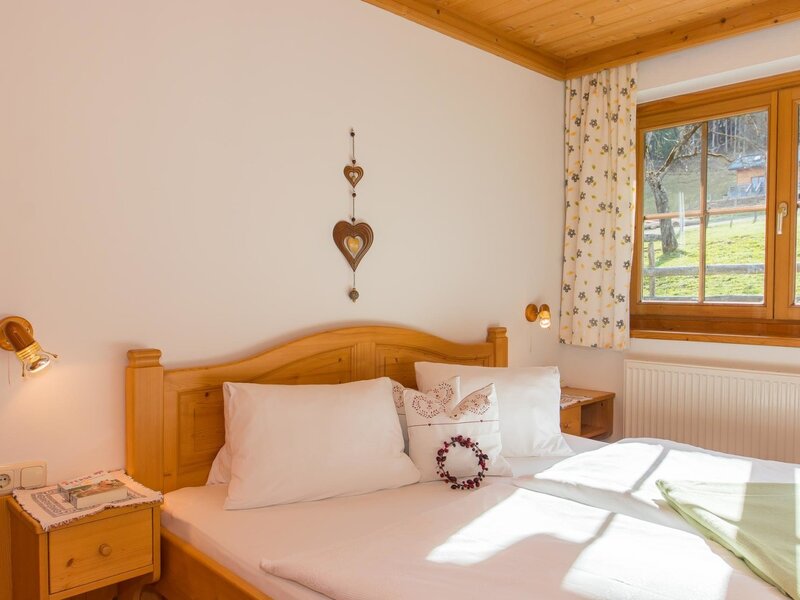 Double bedroom in the Farm House with a wooden bed, nightstands, wall lamps, and a window offering views of the outdoor area.