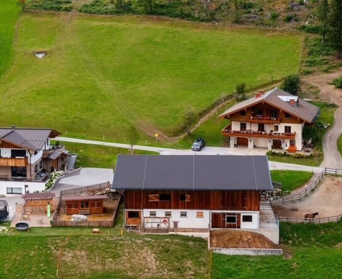 Aerial view of the idyllic farmhouse, surrounded by lush green meadows and rolling hills.