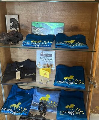 A charmingly arranged wooden display cabinet at the farmhouse, featuring branded T-shirts and souvenirs.
