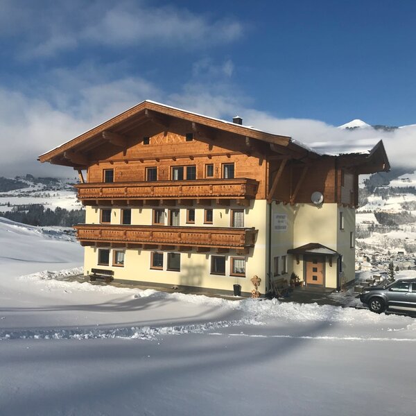 The multi-story farm house, featuring traditional wooden balconies, stands in a snow-covered landscape with panoramic views of the valley and mountains. The multi-story farm house, featuring traditional wooden balconies, stands in a snow-covered landscape with panoramic views of the valley and mountains.
