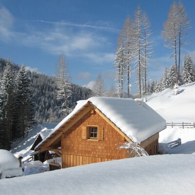 The farmhouse exterior, featuring wooden construction and a snow-covered winter landscape.