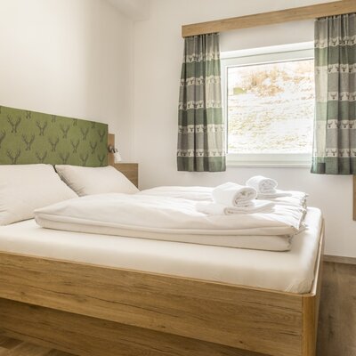 Bedroom with a modern wooden double bed, patterned headboard, and matching curtains.