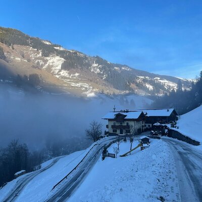 The Farm House set in a snowy mountain valley, with a clear road leading to the property and distant fog.