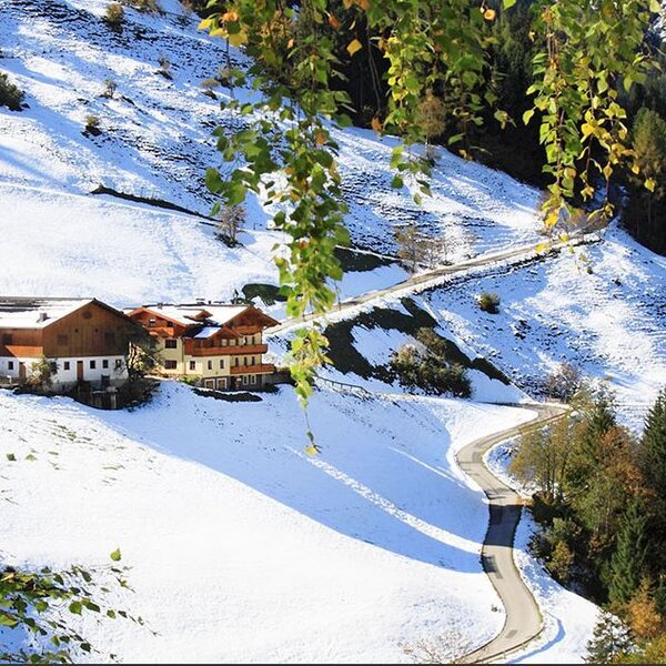 The farmhouse surrounded by snow-covered slopes and an access road.