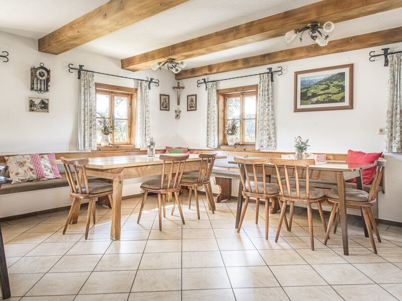 The farmhouse dining area with wooden tables, chairs, bench seating, and exposed ceiling beams.