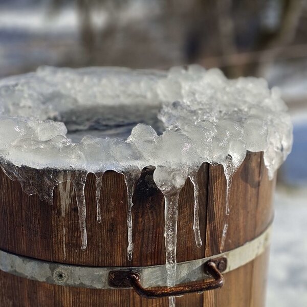 A wooden barrel covered in ice and icicles at the farmhouse.