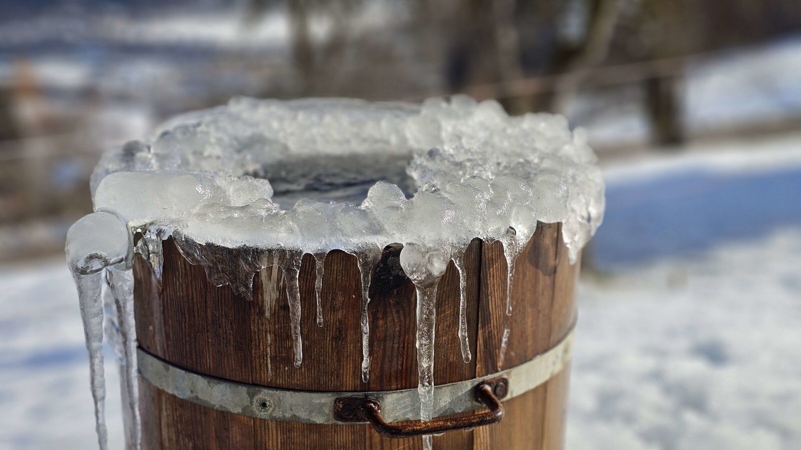 A wooden barrel covered in ice and icicles at the farmhouse.