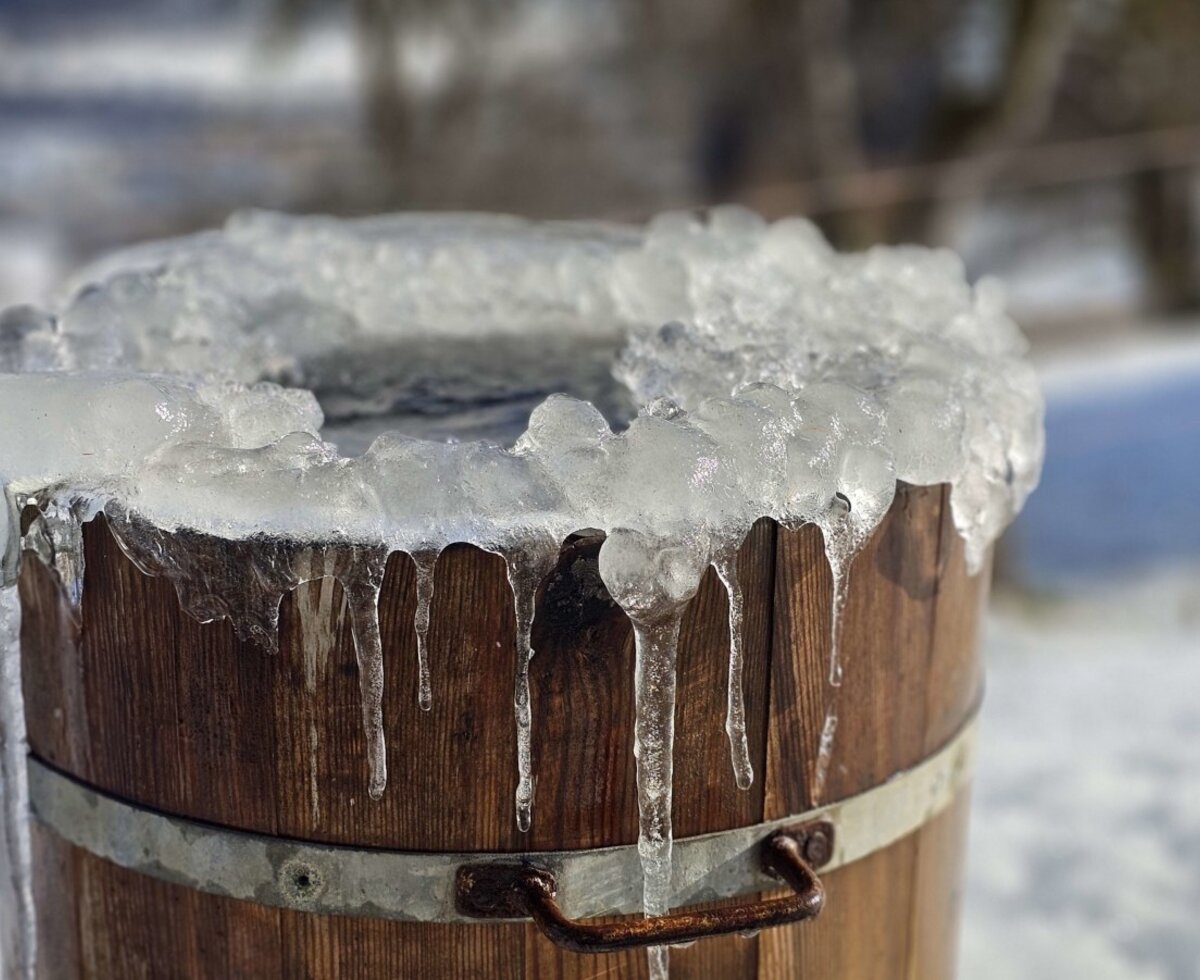 A wooden barrel covered in ice and icicles at the farmhouse.