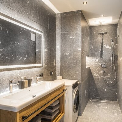 Modern bathroom with a double vanity, washing machine, walk-in shower, and heated towel rail.