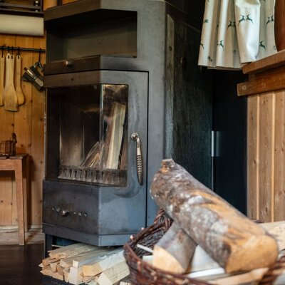 A cozy wood-burning stove in the Alm, with a basket of firewood for comforting warmth.