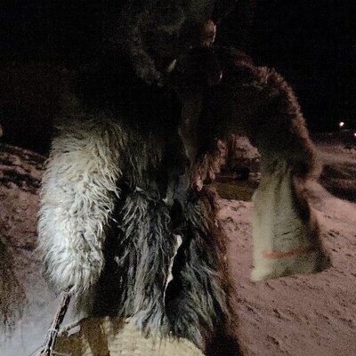 A traditional Krampus figure in the snowy outdoor area of the farmhouse.