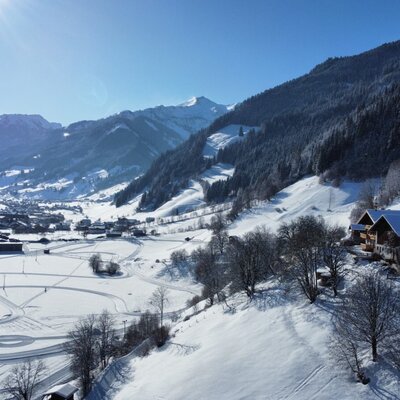 View of the farmhouse, the snowy valley, and the surrounding mountains.