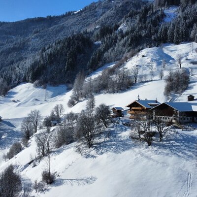 The farmhouse in a snowy mountain landscape with traditional buildings and views of the mountains and valley.