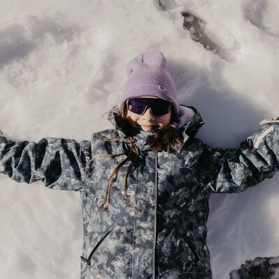 A child making a snow angel in the snow, showcasing winter play opportunities at the farmhouse.