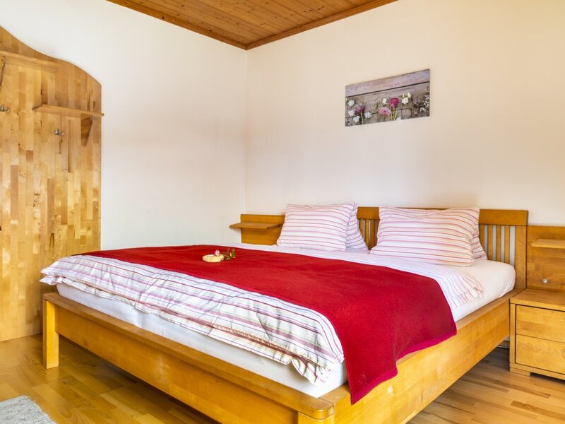 Bedroom in the Farm House featuring a wooden double bed, integrated bedside tables, and a wooden wall panel with hooks.