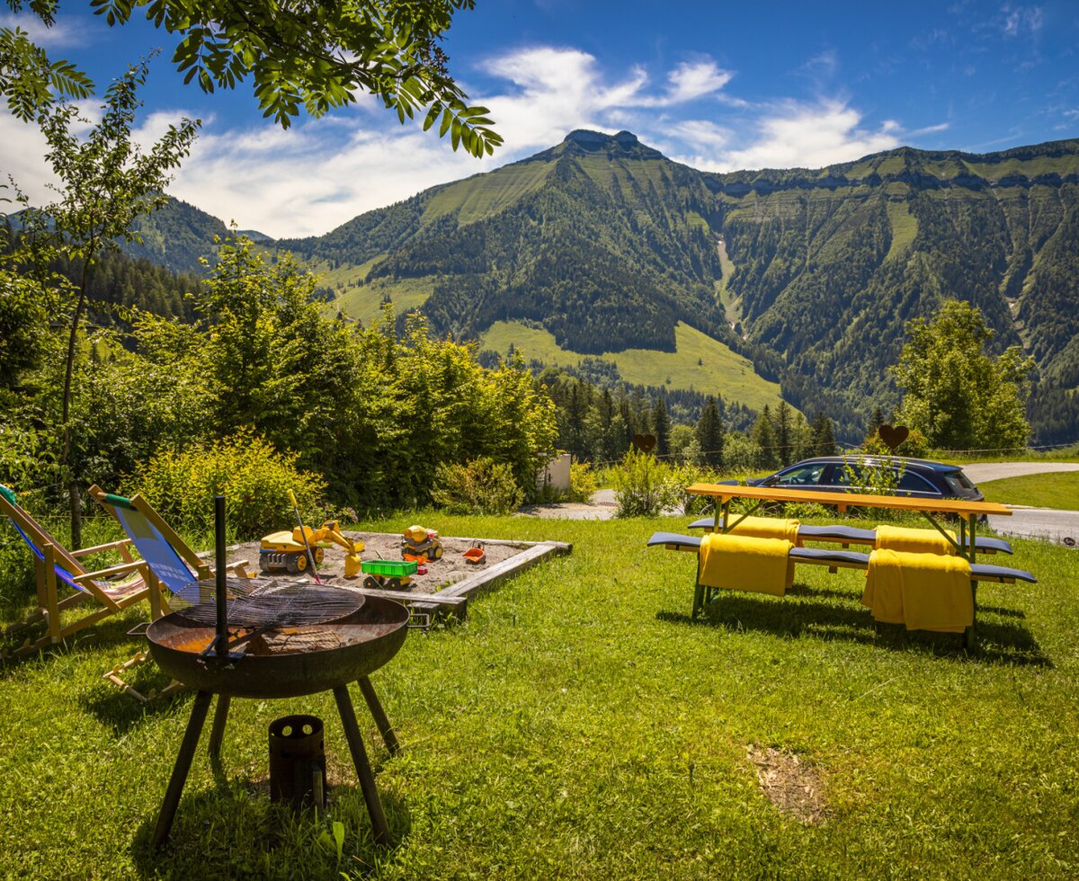 The Farm House offers an outdoor garden with a barbecue, lounge chairs, a children's sandbox, and a picnic table, all overlooking the mountains.