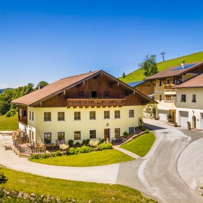 The Reitlhof farm house property consists of several buildings nestled within a green mountainous landscape.