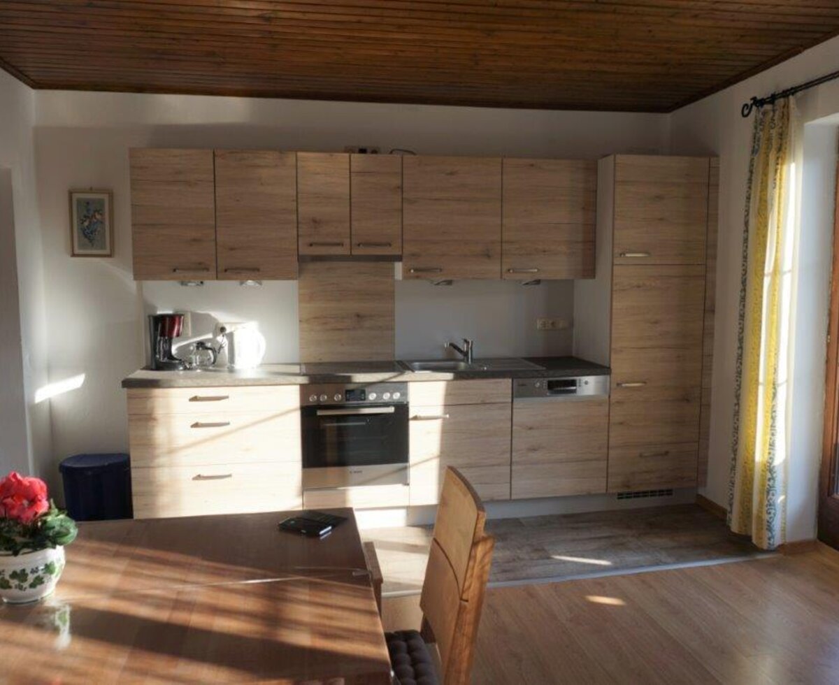The kitchen area of the Farm House features an oven, dishwasher, and coffee maker, with a door opening to a balcony or terrace.