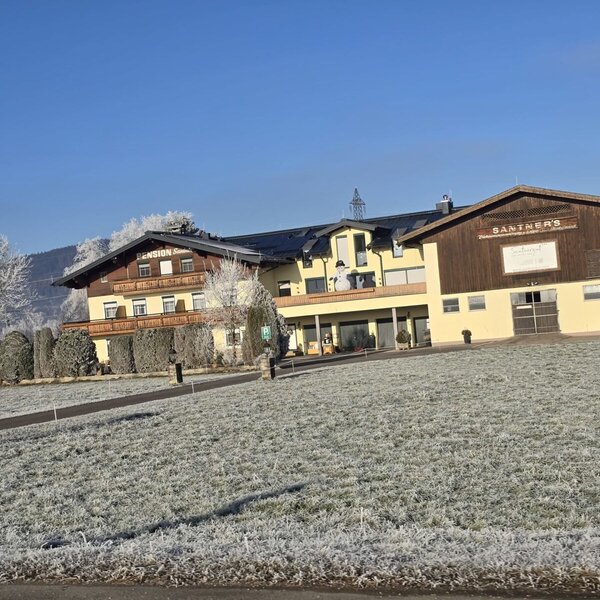 The farm house exterior features the guest accommodation wing with balconies and an adjacent farm building, set against a frosted winter landscape.