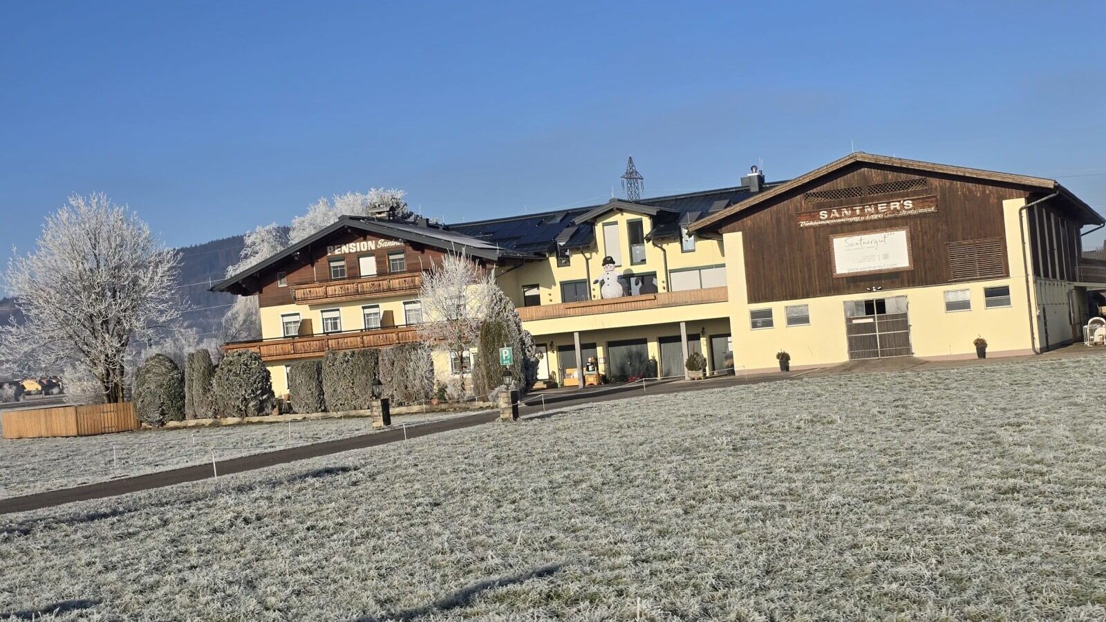The farm house exterior features the guest accommodation wing with balconies and an adjacent farm building, set against a frosted winter landscape.