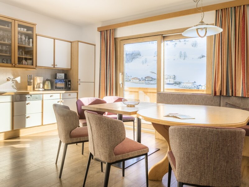 Fully equipped kitchen and dining area with a dining table, corner bench, and chairs in the farmhouse, offering a view of the snowy landscape.