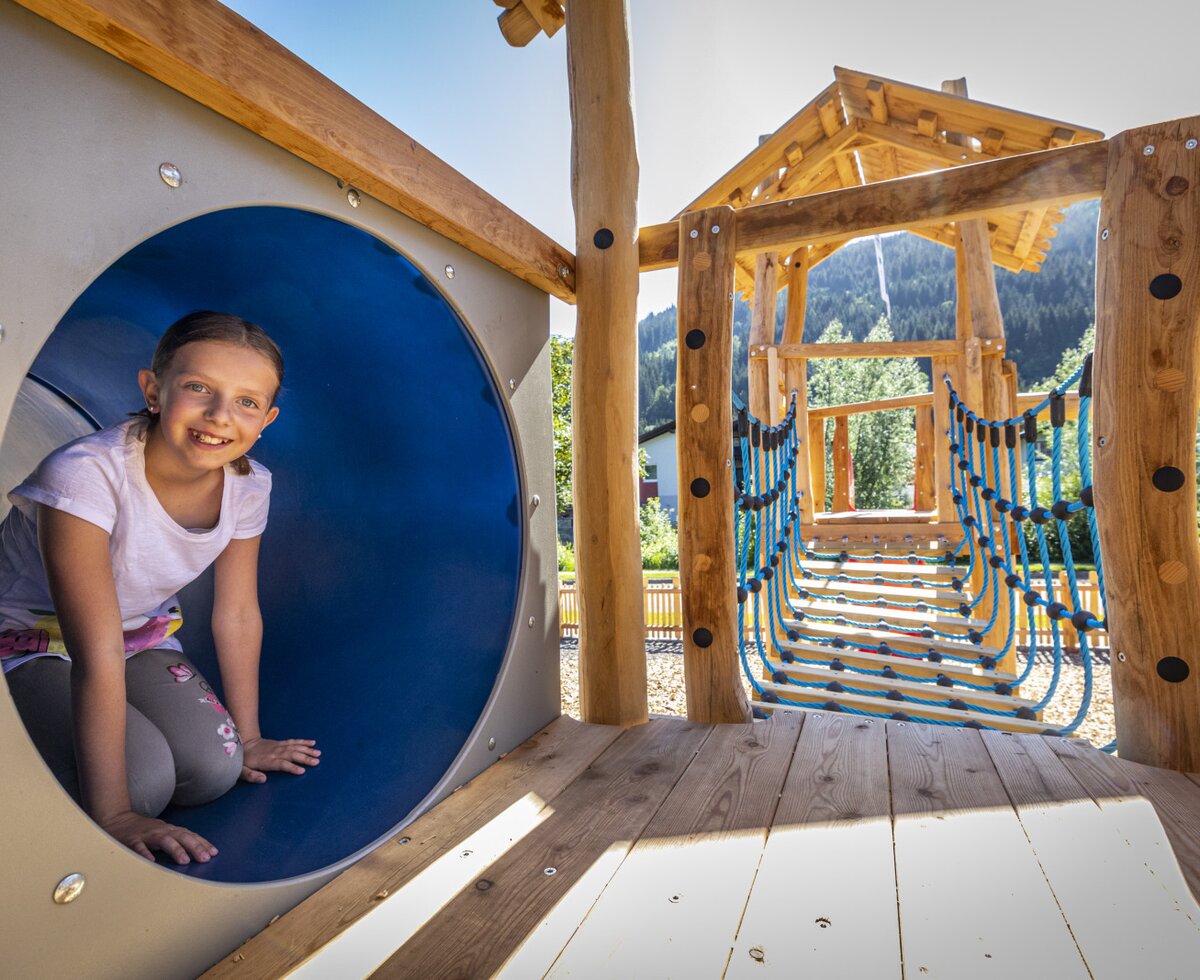 The playground at the Farm House features a wooden climbing structure, a blue tunnel, and a rope bridge.