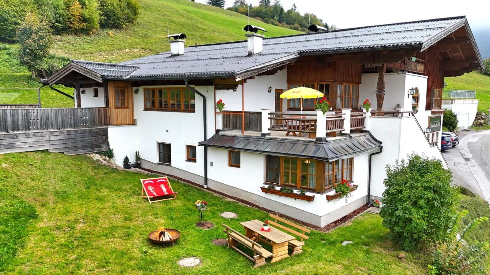The charming Ferienwohnung featuring a well-kept garden with outdoor seating, a fire pit, and an inviting balcony.