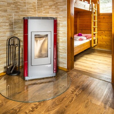 The farmhouse offers a stove with fireplace tools, adjacent to a bedroom featuring wooden bunk beds.