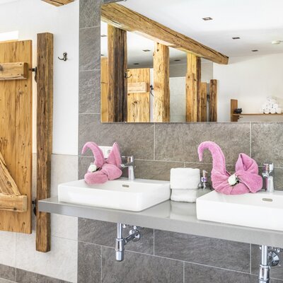 Bathroom at the farmhouse featuring double sinks, a large mirror, and rustic wooden elements.