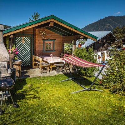 The new log cabin at the farmhouse includes an outdoor dining area, a barbecue, and a hammock, with mountain views.