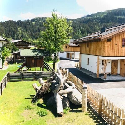 The farm house exterior includes a garden play area with a slide and views of the forested mountains.