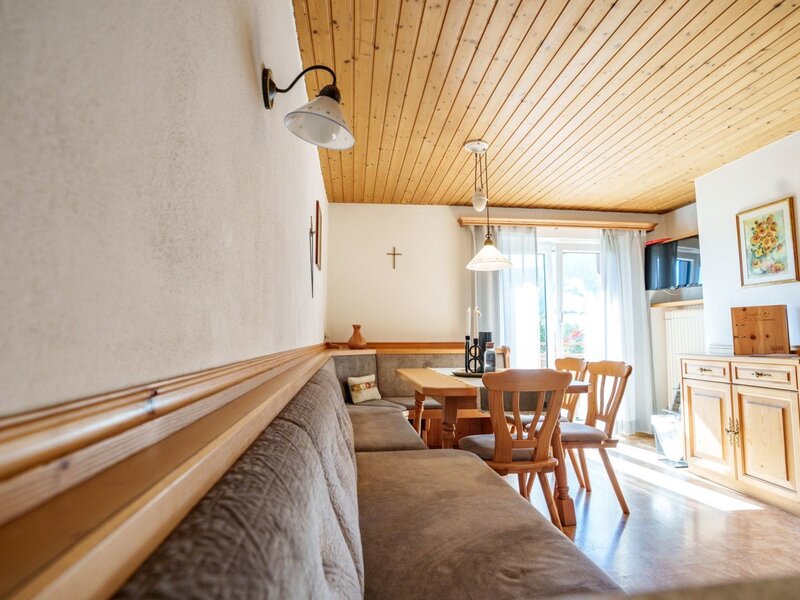 Dining area of the apartment in the farmhouse with a wooden table, corner bench, and balcony access.