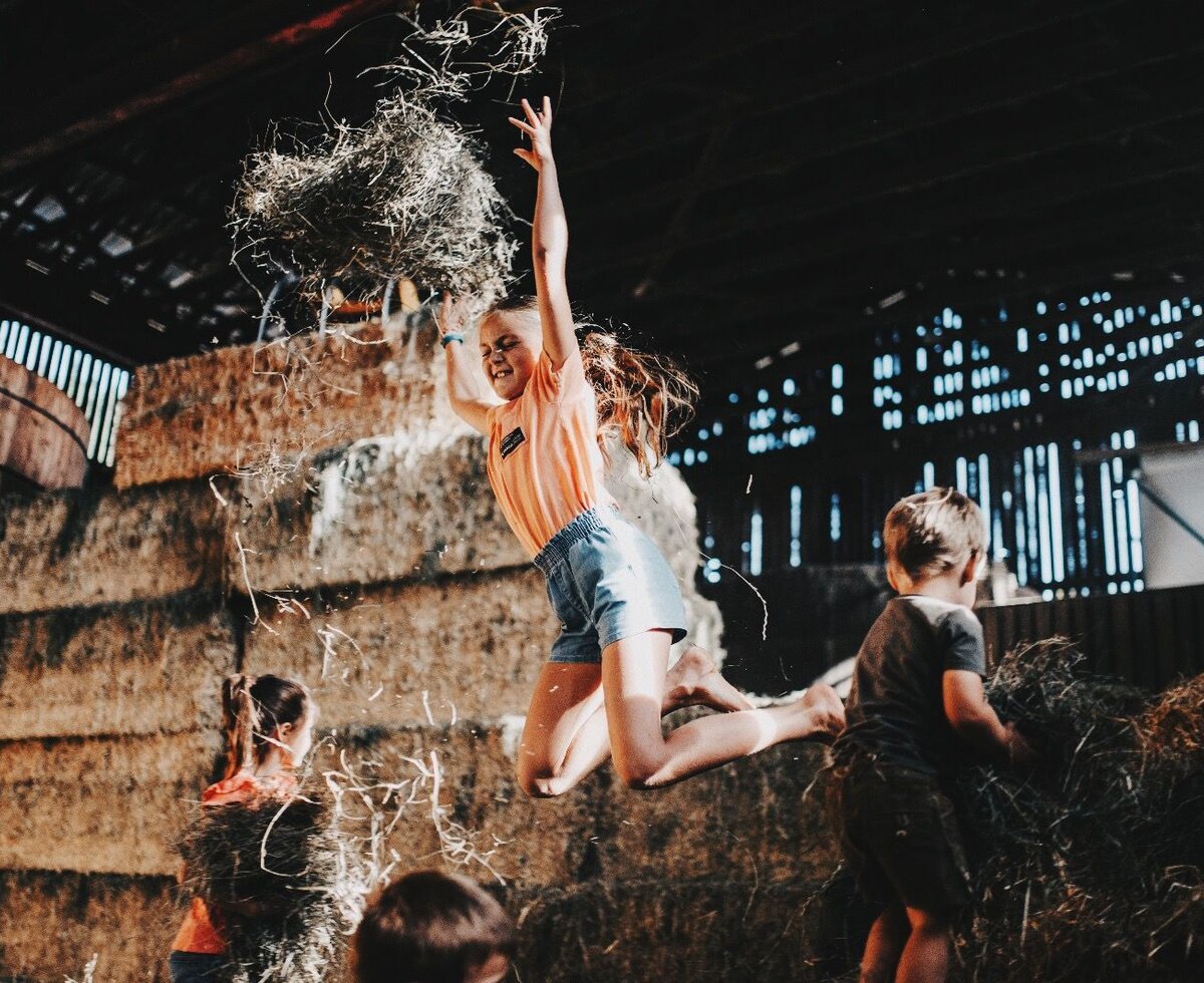 Children playing with hay in the barn of the farmhouse.