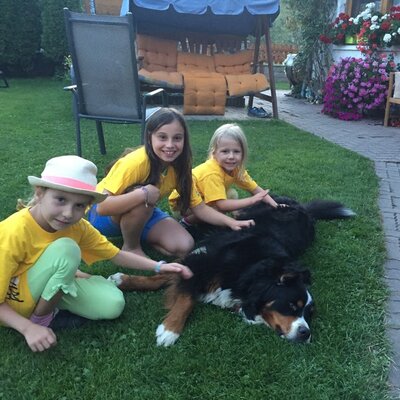 The garden at the farmhouse, with children playing on the grassy lawn alongside a dog.