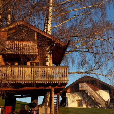 The treehouse at the farmhouse with its balconies and a barbecue area, offering views of the surrounding landscape and mountains.