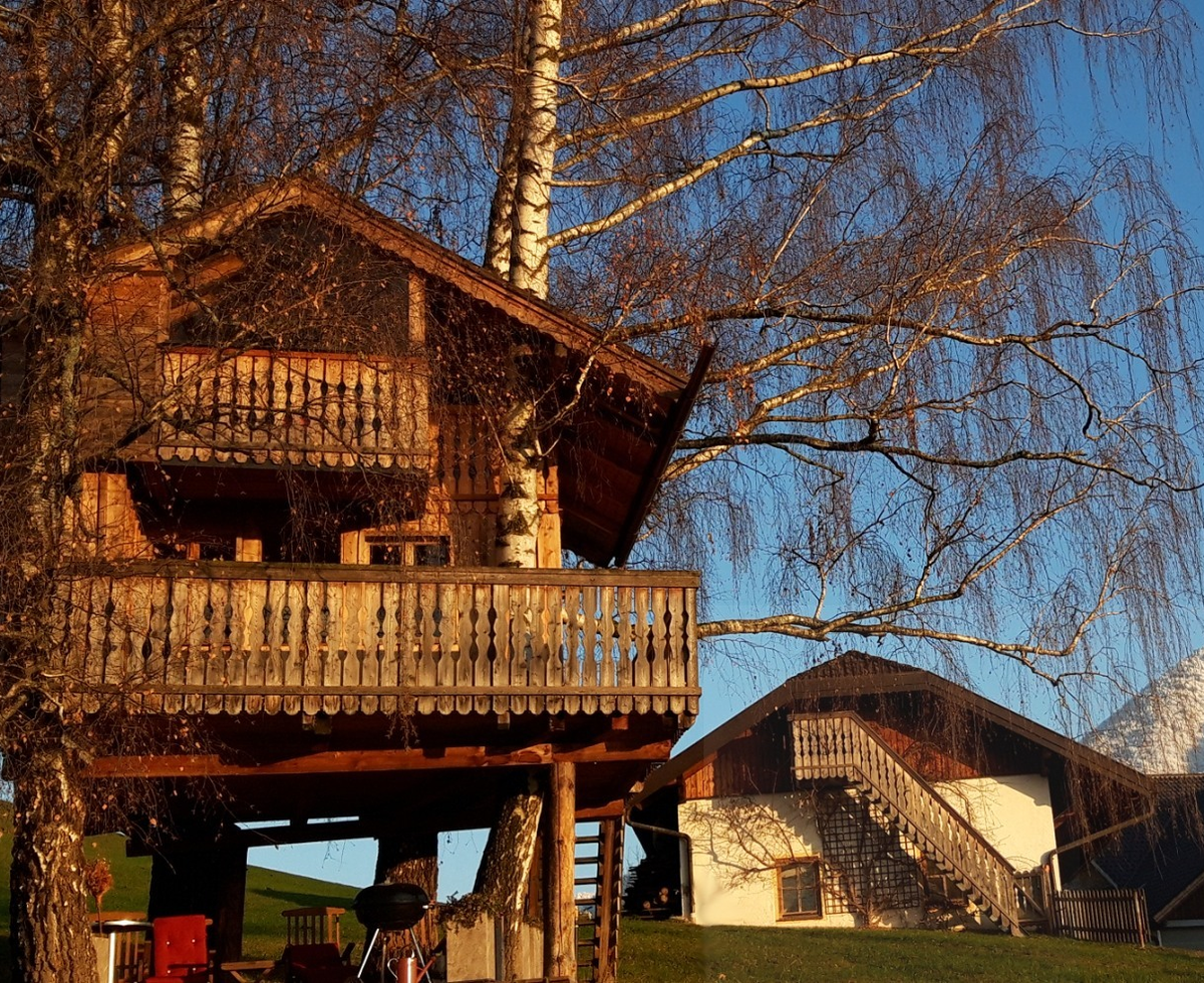 The treehouse at the farmhouse with its balconies and a barbecue area, offering views of the surrounding landscape and mountains.