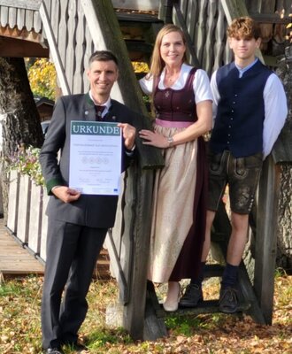 The host family of the farmhouse in traditional attire presents an award.