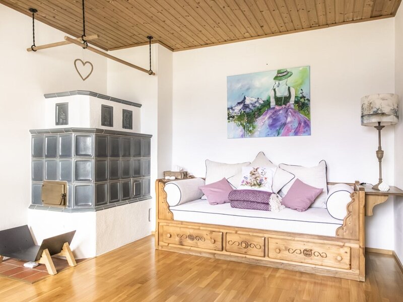 Living area in the farmhouse with a traditional tiled stove and a wooden daybed.