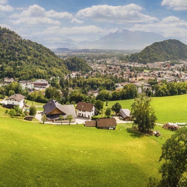 Scenic view of the farmhouse, surrounded by lush green meadows with a panoramic vista of the town and mountains.