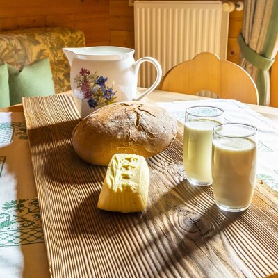 Fresh bread, butter, and milk on a wooden serving board in the Farm House dining space.